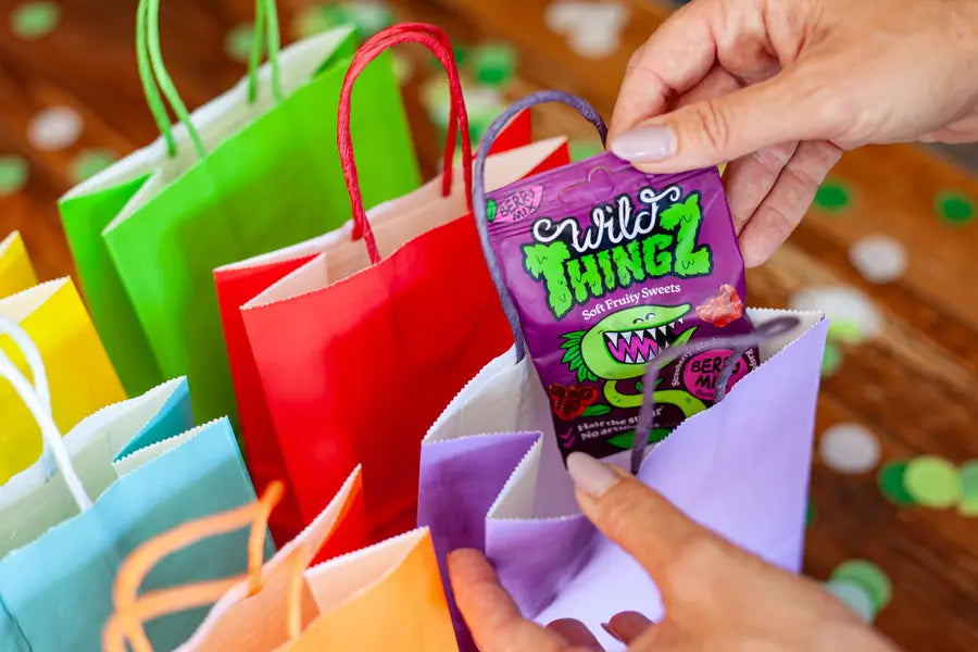 Hands filling colourful party bags with Berry Mix