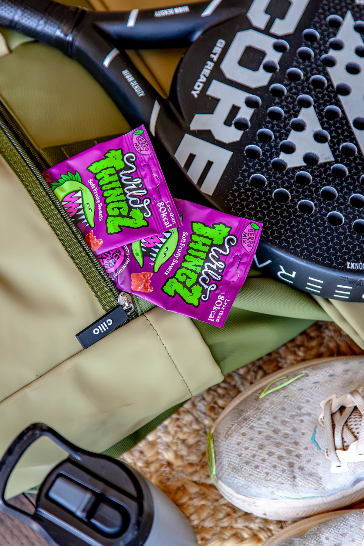 Two bags of Berry Mix in a sports bag next to a padel racket and trainers