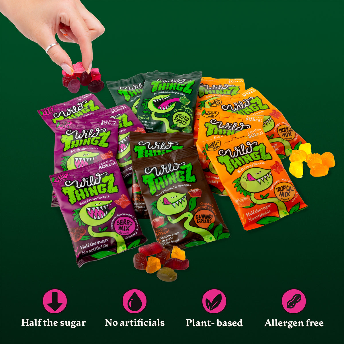 Bags of all four Wild Thingz flavours with gummies spilling out on a dark green background: half the sugar, no artificials, plant-based, allergen free