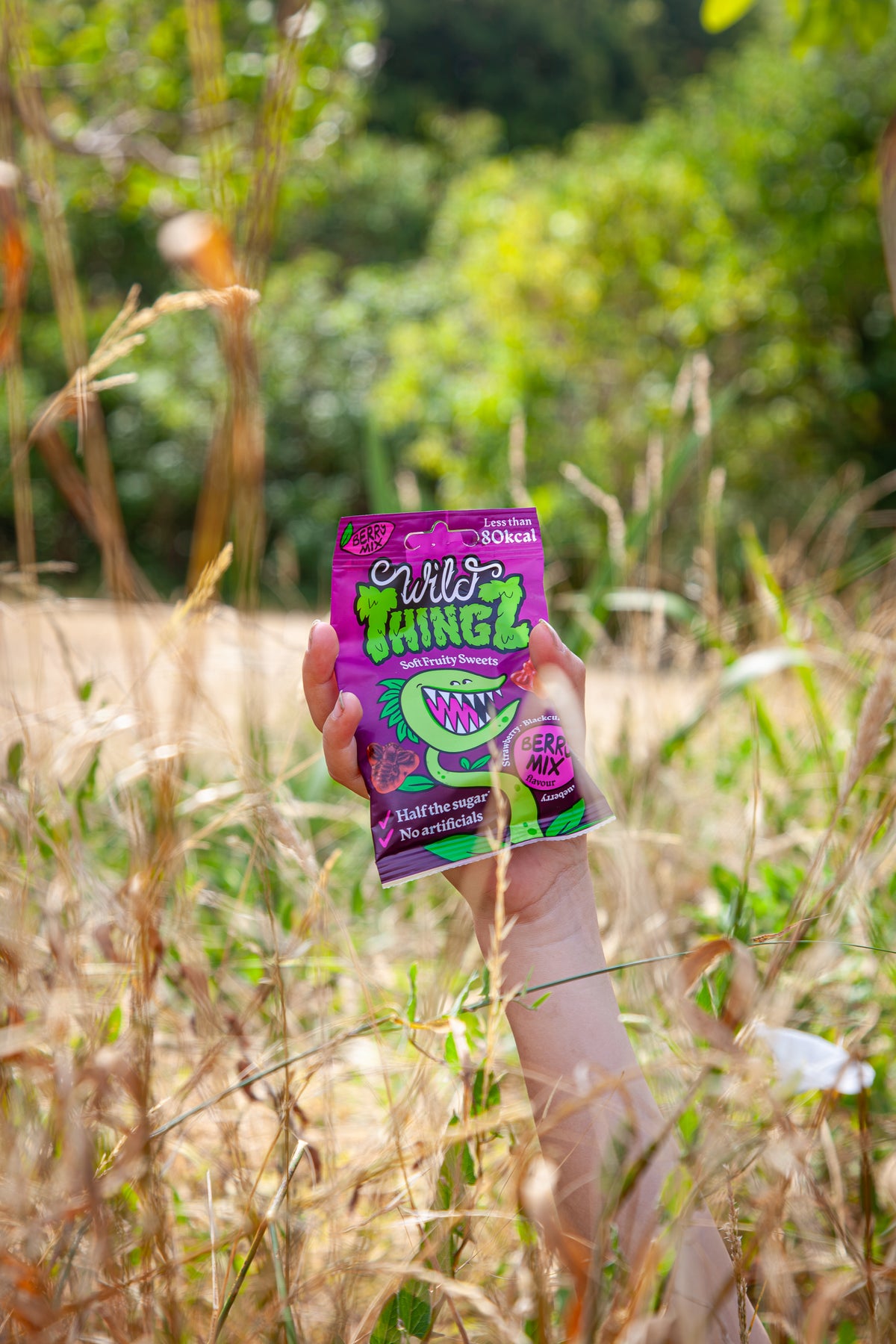 A bag of Berry Mix held up among tall summer grass