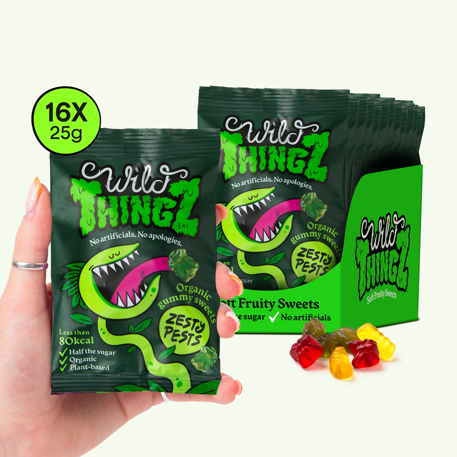 Hand holding a 25g bag of Wild Thingz Organic Zesty Pests in front of a case of 16 bags